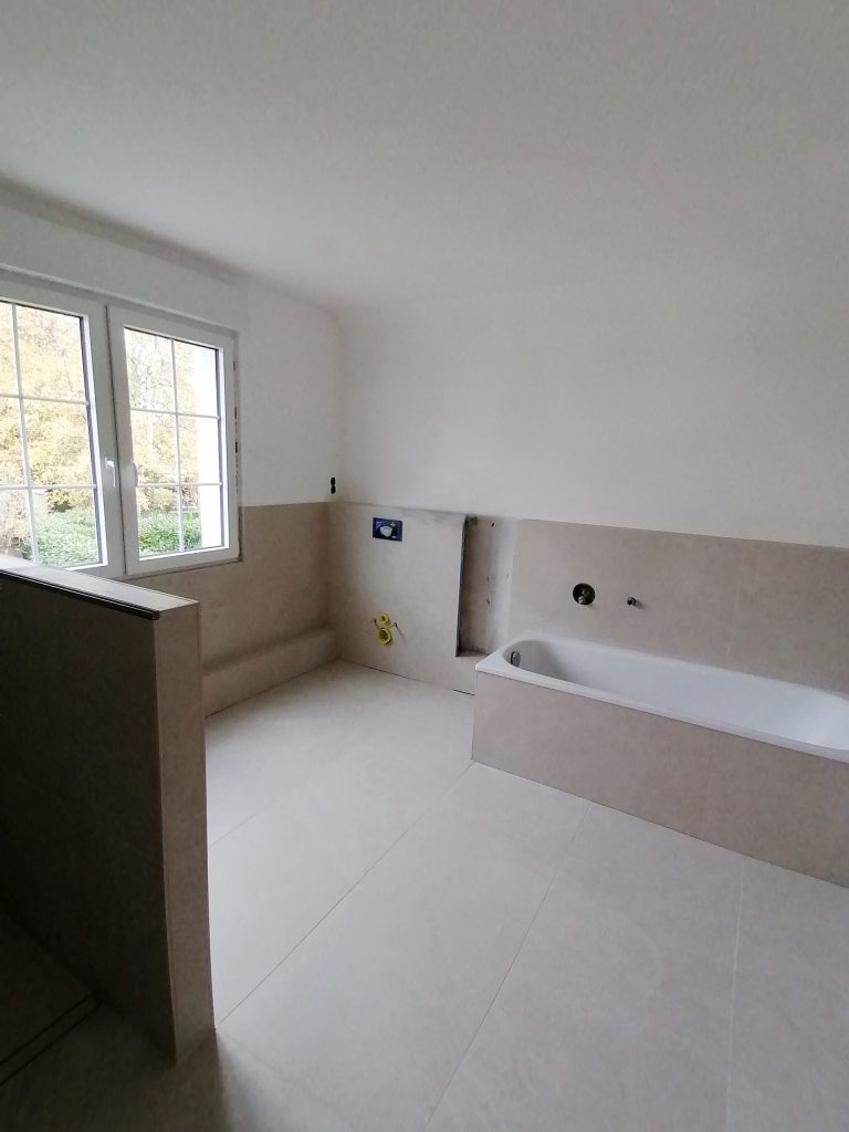 Bad-Rohbau: Modernes Badezimmer während der Renovierung mit beigen Fliesen.