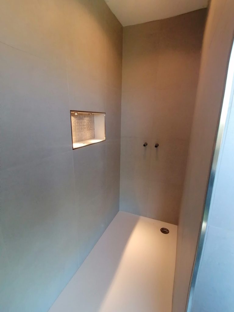 Kombibad: Weiße Badewanne direkt neben einem Waschtisch mit rundem Spiegel.
