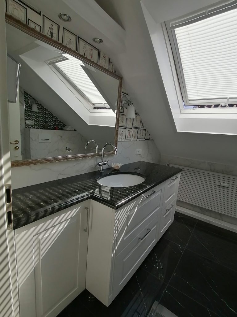 Waschtisch unter Schräge: Weißes Waschbecken in einem Badezimmer mit Dachfenster.