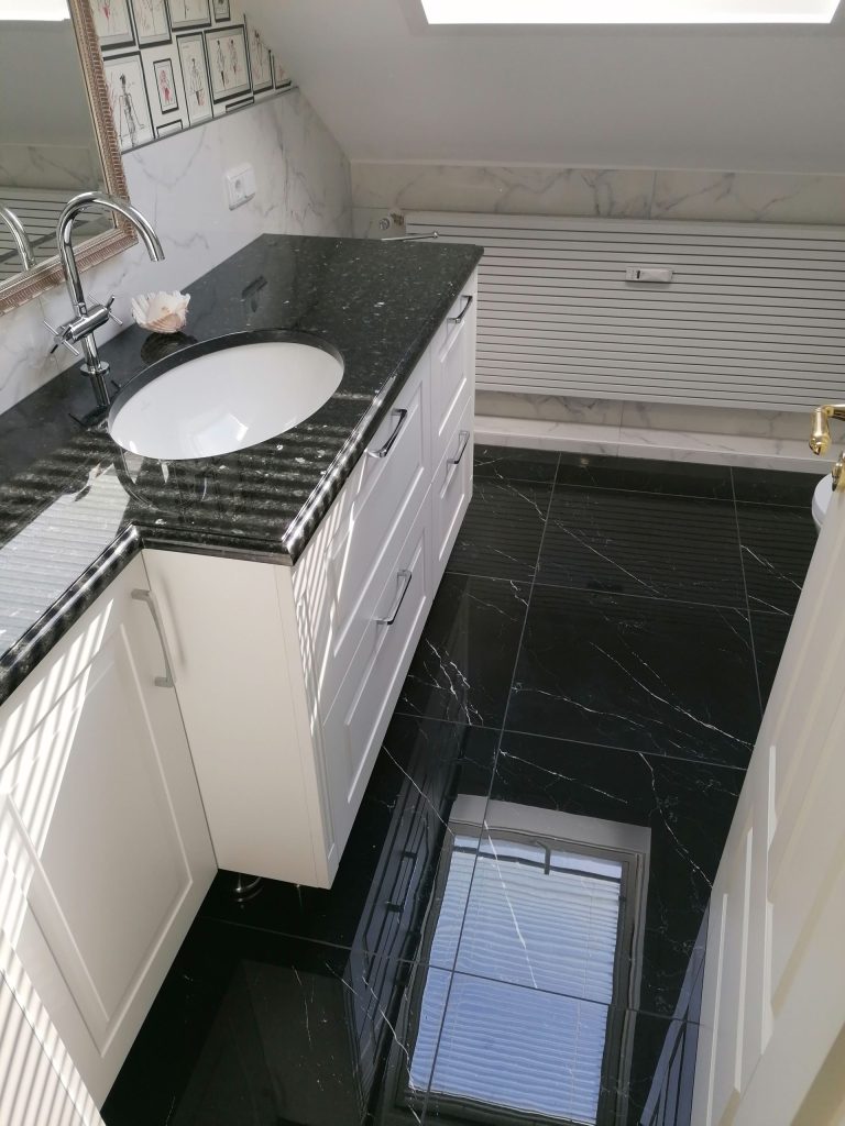Duschraum: Großzügige Dusche mit gemustertem Fliesenboden und schwarzer Sitzbank.