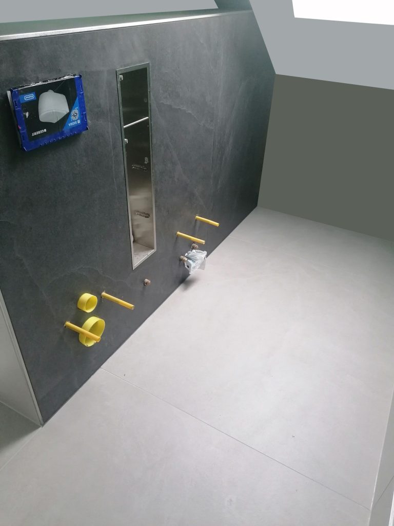 Bodenabfluss: Grauer Fliesenboden in einer Dusche mit punktförmigem Abfluss.