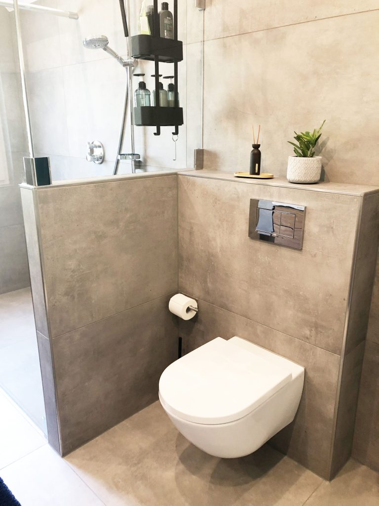 Eckregal: Integrierte Ablagefächer in einer weiß gefliesten Dusche.